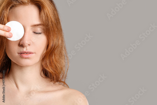 Beautiful woman with makeup sponge on grey background photo