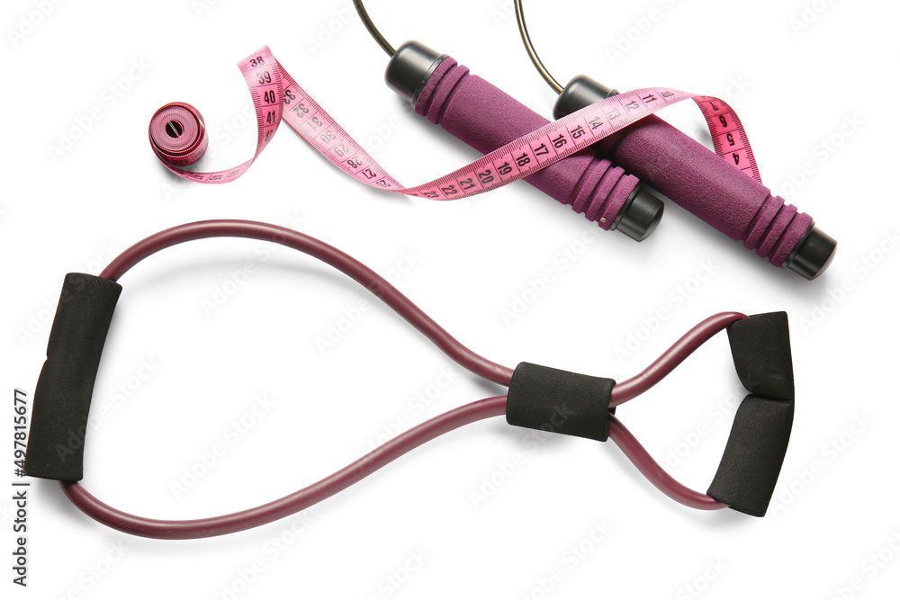 Stylish skipping rope, fitness expander and measuring tape on white background Stylish skipping rope, fitness expander and measuring tape on white background