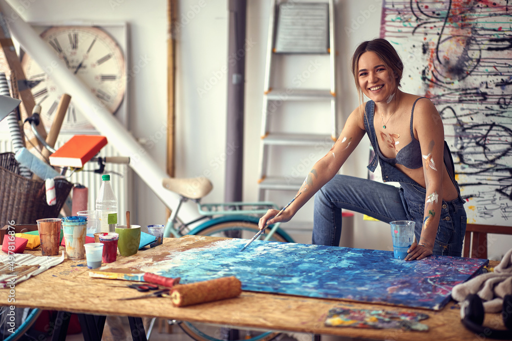 A young sexy and relaxed female artist is posing for a photo in her studio. Art, painting, studio A young sexy and relaxed female artist is posing for a photo in her studio. Art, painting, studio