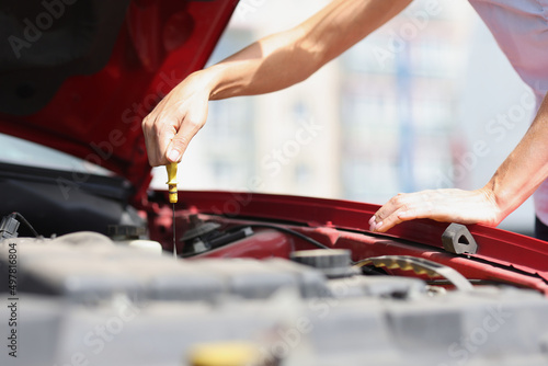 Driver checks oil level in car engines closeup