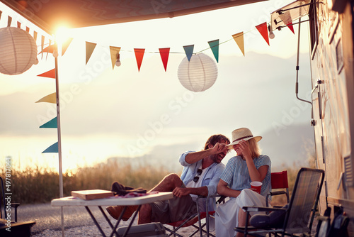 Couple in love. Sitting in front of camper rv. Having fun. Outdoors summer party. Fun, togetherness, lifestyle, nature concept.