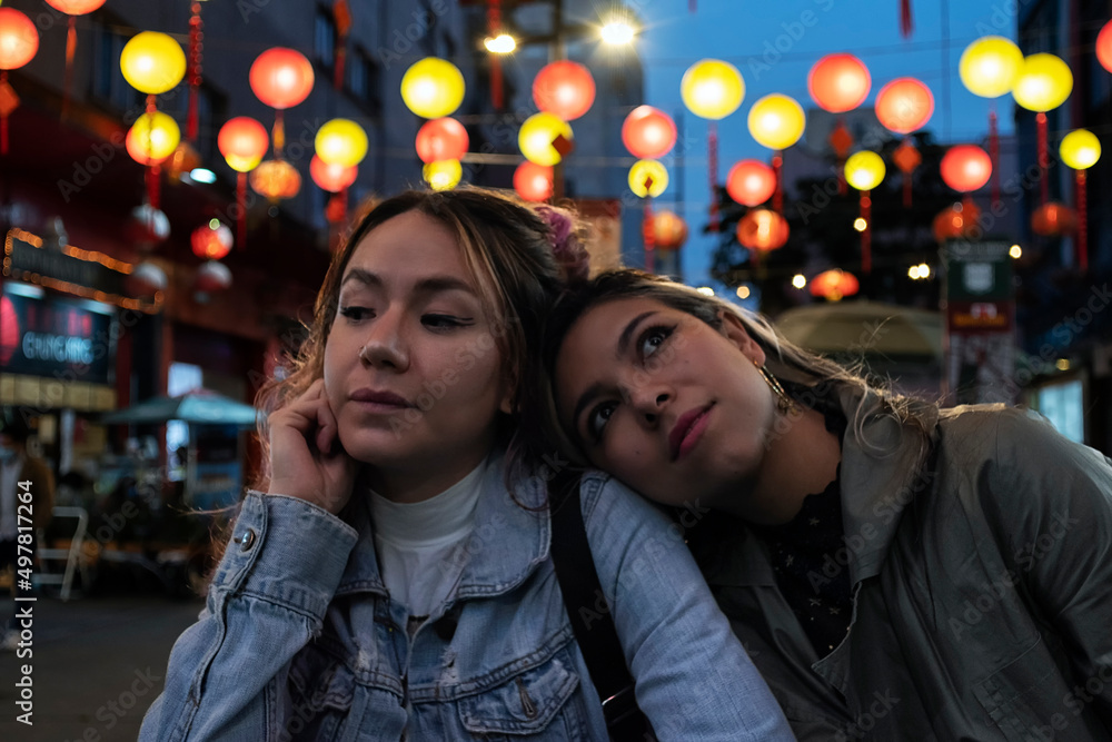 Night portrait of two best friends ladys in the street. Colorful lights at the background