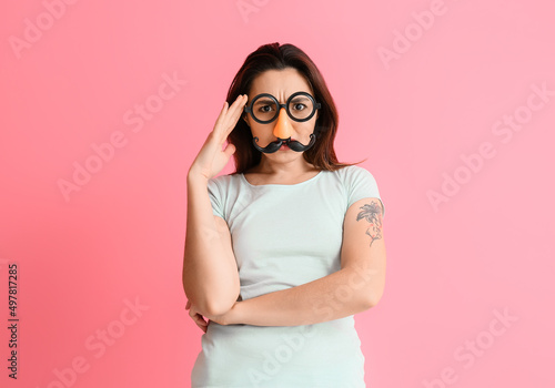 Young woman in funny disguise on pink background. April fools' day celebration © Pixel-Shot