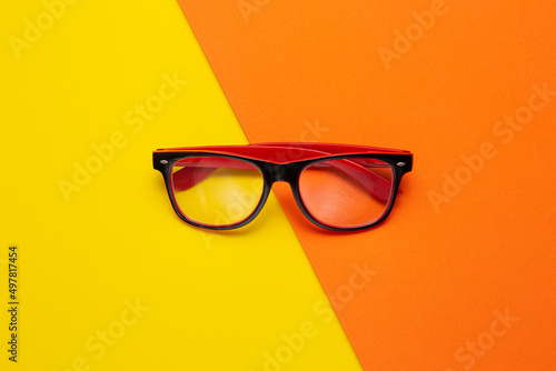 Stylish shaped glasses on color background, top view