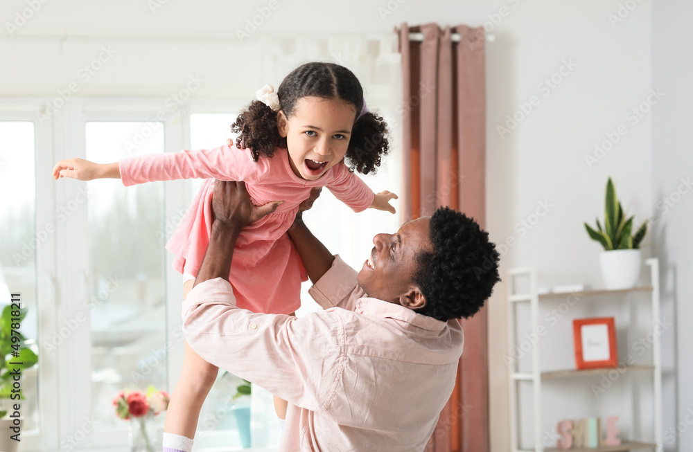 Happy African-American man and his little daughter playing at home Happy African-American man and his little daughter playing at home