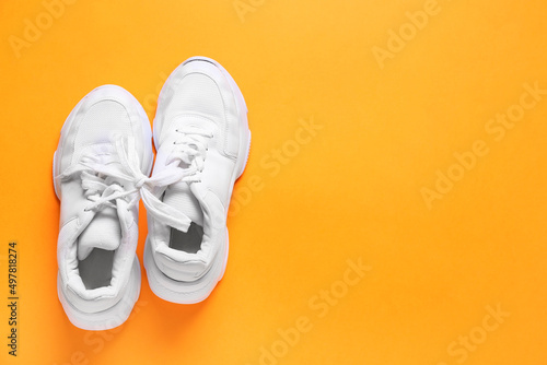 Shoes with tied laces on orange background. April Fool's Day prank