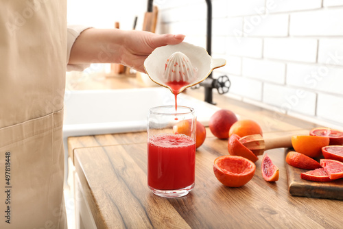 Woman making fresh orange juice in kitchen