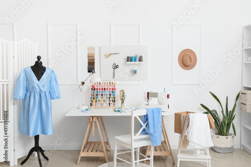 Interior of stylish atelier with tailor's workplace, mannequin and pegboard