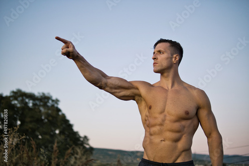 Portrait of muscular aggressive man showing muscle, isolated on a beautiful landscape.