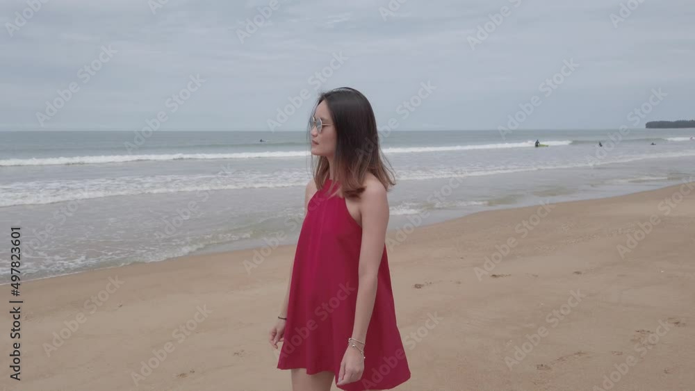 Young asian woman wear red dress and walking relaxing on the beach at summer vacation holidays in slowmotion Young asian woman wear red dress and walking relaxing on the beach at summer vacation holidays in slowmotion