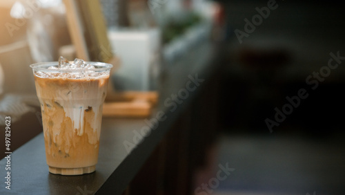 Ice coffee on a plastic cup with cream being poured into it showing the texture © pariwatpannium