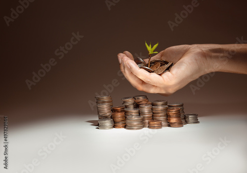 plant growing from coins and a hand holding coins with a stack of  coins