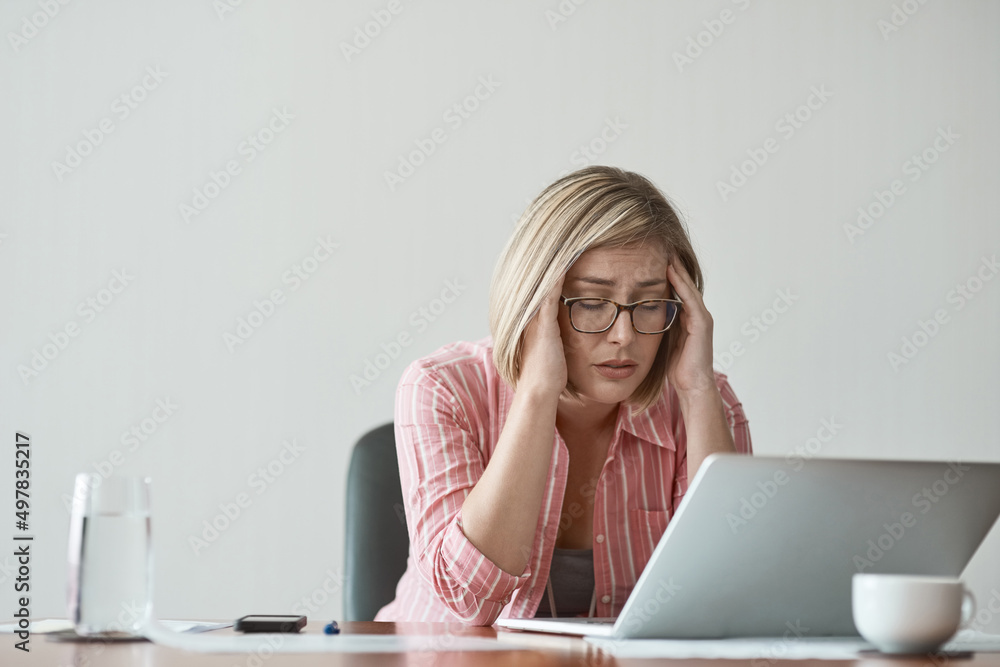 These deadlines are giving me a headache. Studio shot of a businesswoman looking stressed out while working on a laptop against a grey background. These deadlines are giving me a headache. Studio shot of a businesswoman looking stressed out while working on a laptop against a grey background.