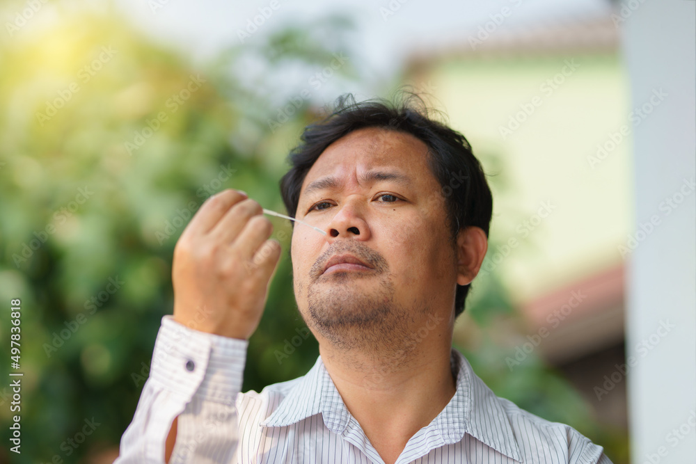 Man self test for COVID-19 home test kit in the morning before go to working. Asian man using coronavirus covid-19 rapid antigen home testing kit, Coronavirus nasal swab test for infection. Man self test for COVID-19 home test kit in the morning before go to working. Asian man using coronavirus covid-19 rapid antigen home testing kit, Coronavirus nasal swab test for infection.