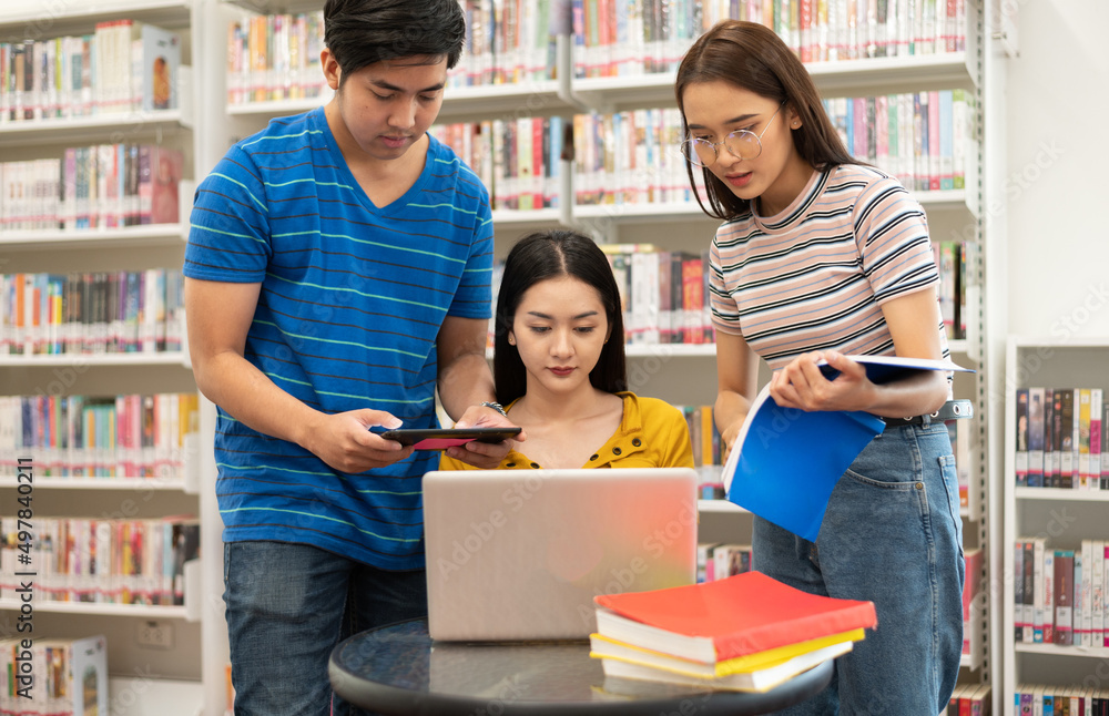 Happy young university students studying with books in library. Happy young university students studying with books in library.