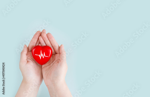 World Hypertension Day. Adult holds a red heart with a heartbeat chart with his hands - a symbol of high blood pressure. Hypertension Day in May 17th. World heart day, world health day.
