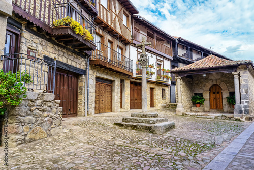 Village square with old traditional houses and stone cross, Mogarraz Salamanca.