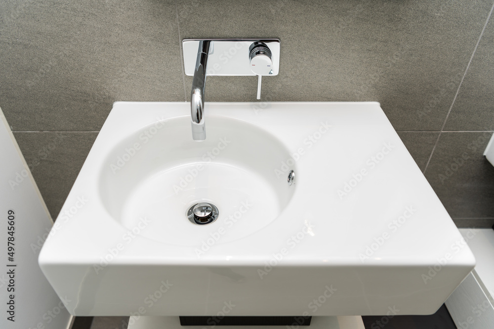 Metal faucet and white ceramic sink in modern bathroom. Metal faucet and white ceramic sink in modern bathroom.