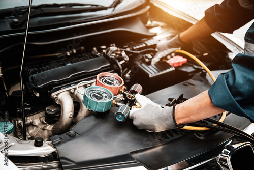 Tableau sur toile Close up hand of auto mechanic using measuring manifold gauge check the refrigerant and filling car air conditioner for fix and checking for repair service support maintenance and car insurance
