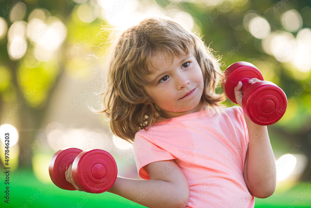 Funny child boy is doing exercises with dumbbells in summer park. Funny child boy is doing exercises with dumbbells in summer park.