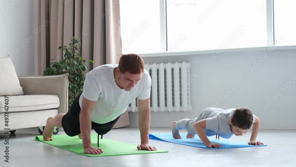 father and son are doing push-ups and having fun at home. diverse family. Sporty toned dad and boy child follow healthy lifestyle exercise taring together. Sport concept. father and son are doing push-ups and having fun at home. diverse family. Sporty toned dad and boy child follow healthy lifestyle exercise taring together. Sport concept.