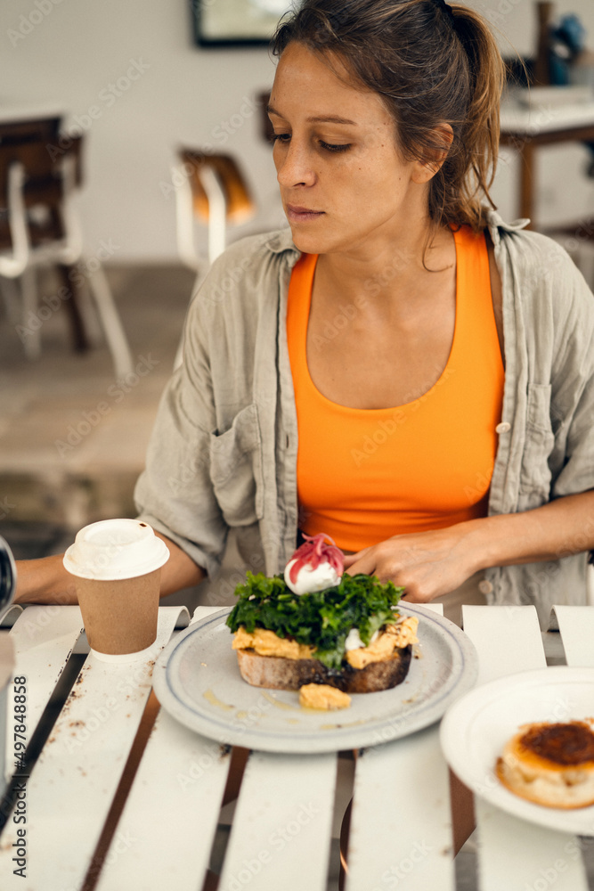 Young beautiful athletic woman drinks coffee from a craft cardboard cup in a cafe.