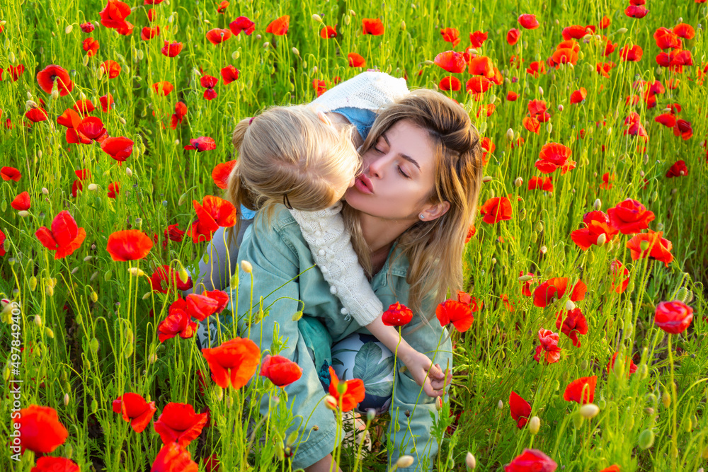 Mother with daughter outdoor in poppy field. Mom hugs lovely child on poppies background. Family in the field of spring blossom flowering meadow. Woman and child laugh and hug. Spring design. Mother with daughter outdoor in poppy field. Mom hugs lovely child on poppies background. Family in the field of spring blossom flowering meadow. Woman and child laugh and hug. Spring design.