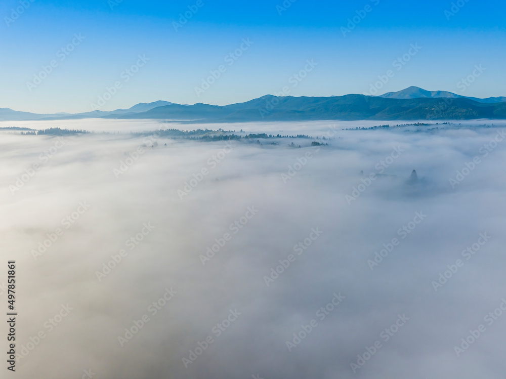Flight over fog in Ukrainian Carpathians in summer. Mountains on the horizon. A thick layer of fog covers the mountains with a continuous carpet. Aerial drone view. Flight over fog in Ukrainian Carpathians in summer. Mountains on the horizon. A thick layer of fog covers the mountains with a continuous carpet. Aerial drone view.