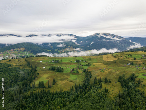 Fototapeta Naklejka Na Ścianę i Meble -  Green slopes of Ukrainian Carpathian mountains in summer. Cloudy morning, low clouds. Aerial drone view.