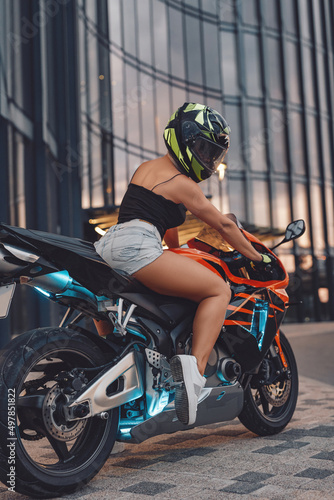 Female biker with helmet riding expensive motorbike outdoors