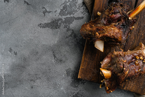 Braised Lamb Shanks with Sauce and Herbs, on gray stone table background, top view flat lay, with copy space for text