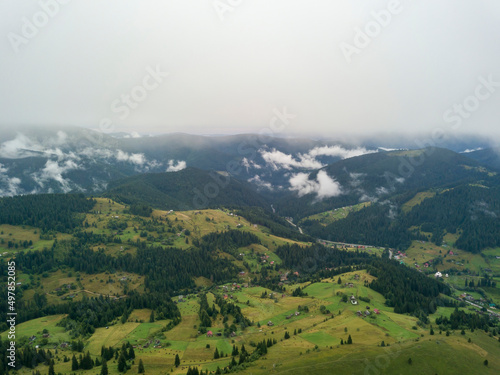 Fototapeta Naklejka Na Ścianę i Meble -  Green slopes of Ukrainian Carpathian mountains in summer. Cloudy morning, low clouds. Aerial drone view.