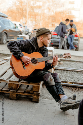 A man plays the guitar in work clothes and on his knees war in Ukraine humanitarian aid

