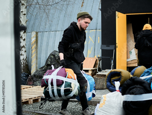 A man in black clothes in a hat loads sleeping bags humanitarian aid during the war in Ukraine
