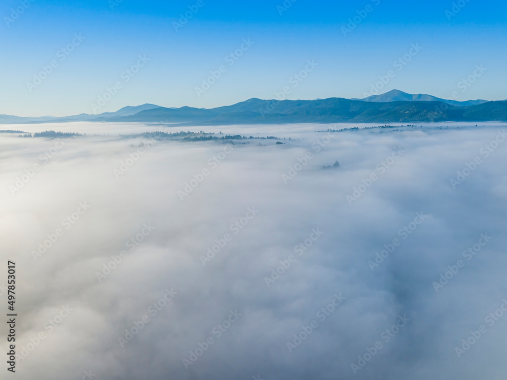 Flight over fog in Ukrainian Carpathians in summer. Mountains on the horizon. A thick layer of fog covers the mountains with a continuous carpet. Aerial drone view. Flight over fog in Ukrainian Carpathians in summer. Mountains on the horizon. A thick layer of fog covers the mountains with a continuous carpet. Aerial drone view.