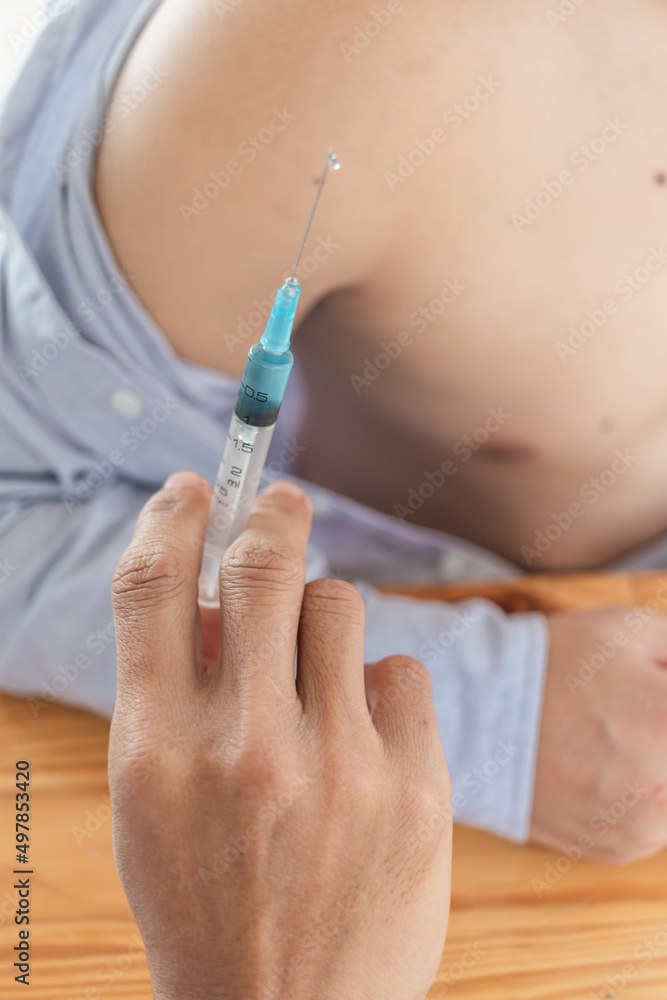 young man undergoes vaccination to prevent spread of coronavirus covid 19 which is currently spreading. doctor is holding a needle to vaccinate young men participating in the program. young man undergoes vaccination to prevent spread of coronavirus covid 19 which is currently spreading. doctor is holding a needle to vaccinate young men participating in the program.