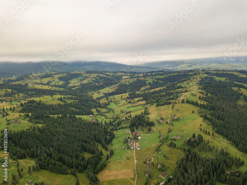 Green slopes of Ukrainian Carpathian mountains in summer. Cloudy morning  low clouds. Aerial drone view.