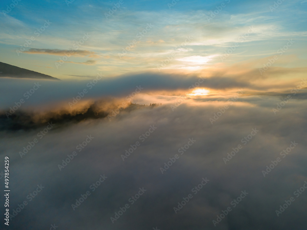 The rays of dawn over the fog in the Ukrainian Carpathians. Aerial drone view.