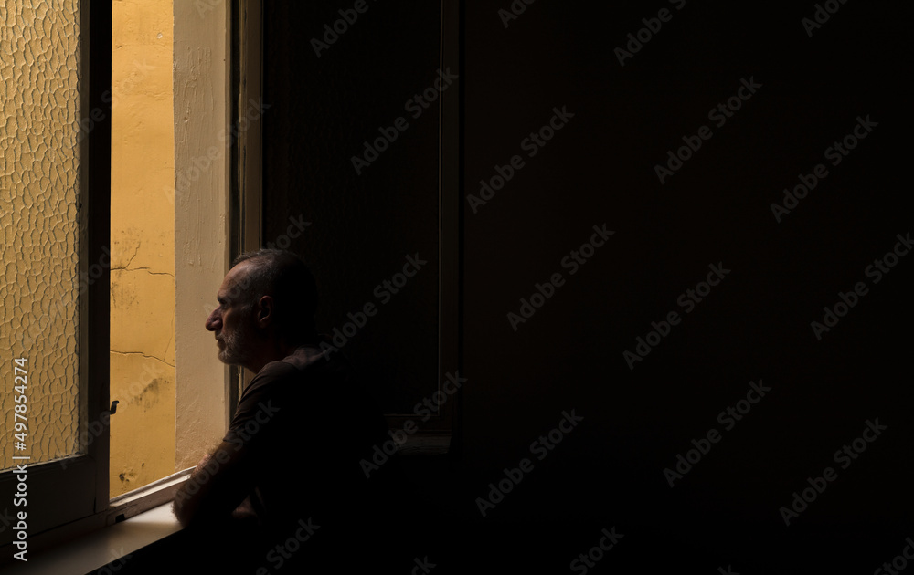 Adult man looking through window in room