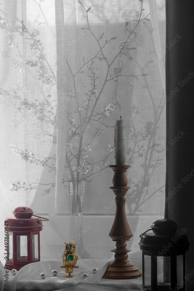 Shadow drawing from a branch of cherry on the window.Household items created an interior composition on the window.Owl, icon lamp, sticks incense, light from the window.