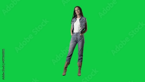 Slow motion of stylish cowgirl style woman in jeans and boots posing at camera. Full body isolated on green screen background