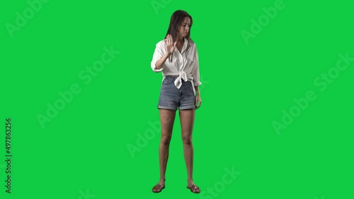 Angry woman showing various negative threat gestures at camera. Full body isolated on green screen background photo