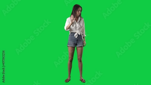 Angry woman showing various negative threat gestures at camera. Full body isolated on green screen background