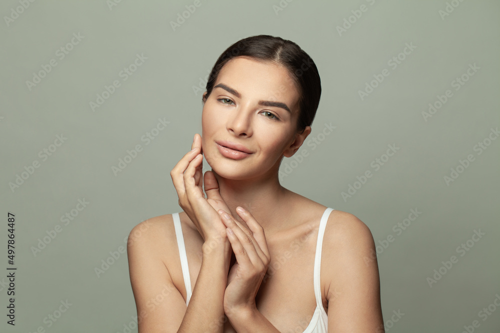 Fototapeta premium Young smiling woman brunette with silky skin on light grey background