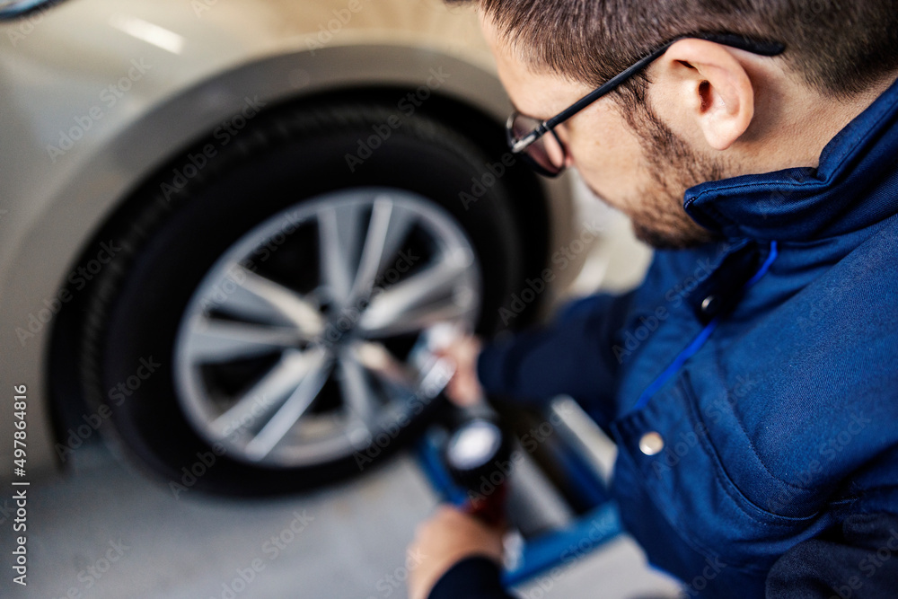 A mechanic inflates the car tire at workshop. A mechanic inflates the car tire at workshop.
