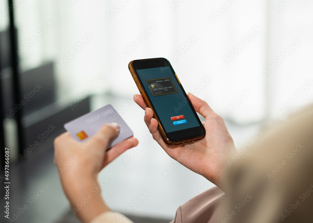 Beautiful businesswoman payment by credit card on mobile phone for online shopping, copy space at background, selective focus at credit card on mobile phone. Young woman shopping online in home office Beautiful businesswoman payment by credit card on mobile phone for online shopping, copy space at background, selective focus at credit card on mobile phone. Young woman shopping online in home office