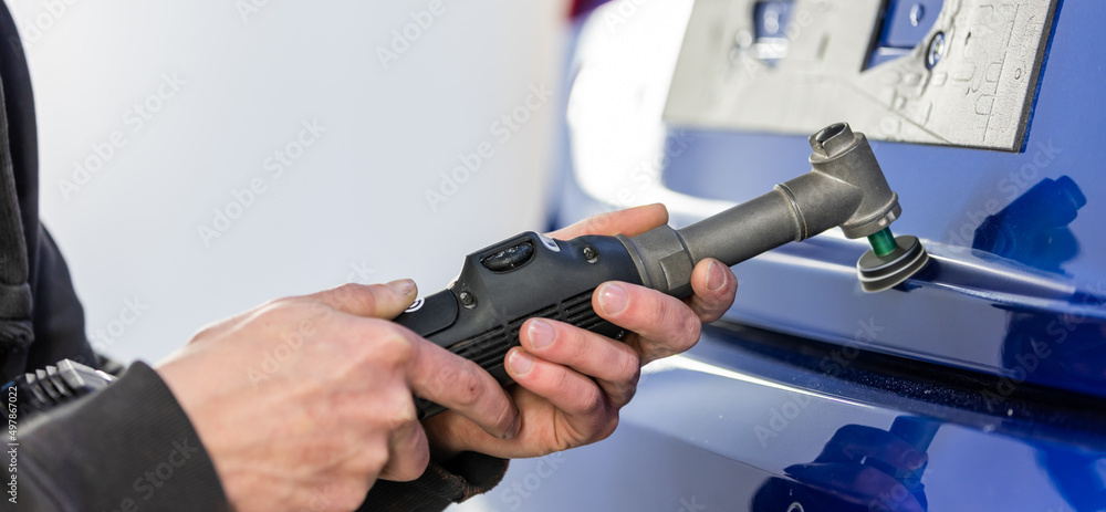 Car details - Man with orbital polisher in a car polishing repair shop, car detailing concept, industry