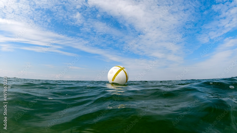 Buoy in the sea with blue sky and interesting clouds