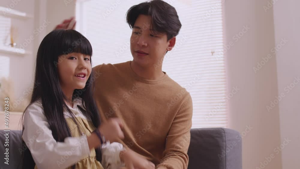 Asian father talking to her baby girl with gentleness while he is resting on her laps on the sofa at home. Asian father talking to her baby girl with gentleness while he is resting on her laps on the sofa at home.