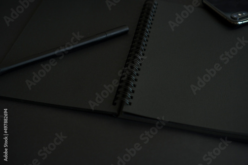 Black notepad and pen on a dark background.